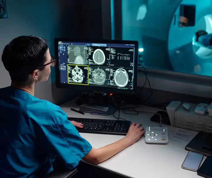 Profesional de la salud revisando imágenes de resonancia magnética cerebral en una estación de trabajo digital, representando la gestión radiológica en la nube con Aquila+ de IMEXHS para centros sin HIS.
