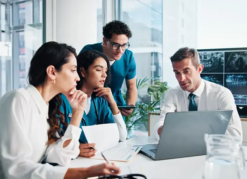 Equipo médico y administrativo analizando resultados radiológicos en laptop, representando la integración de imágenes, reportes y flujos en entornos hospitalarios de alto desempeño con Aquila+ de IMEXHS.